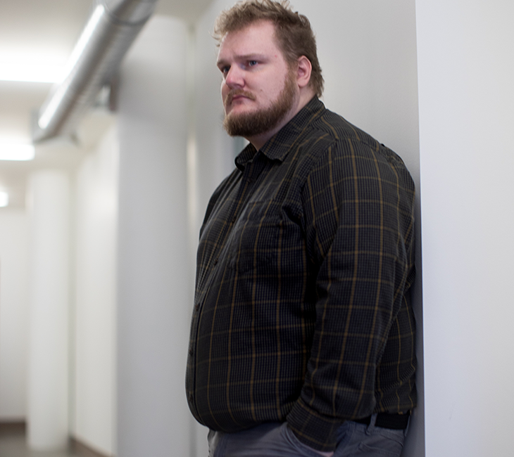 Mand med overvægt står i semiprofil og ser trist ud