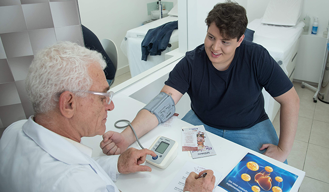 En læger måler blodtryk og taler med patient