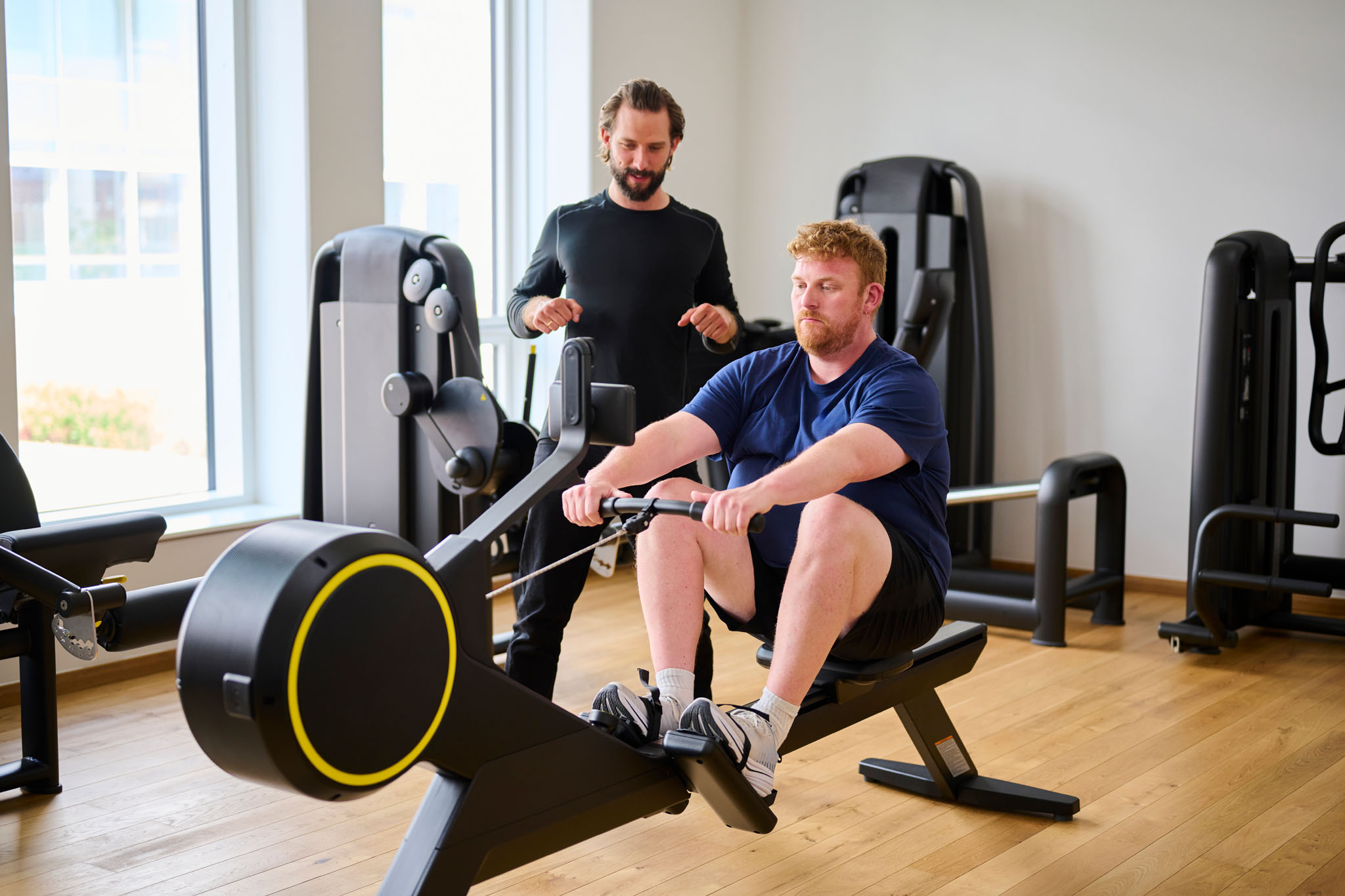 Mand er til roning på romaskine og bliver guidet af en træner.