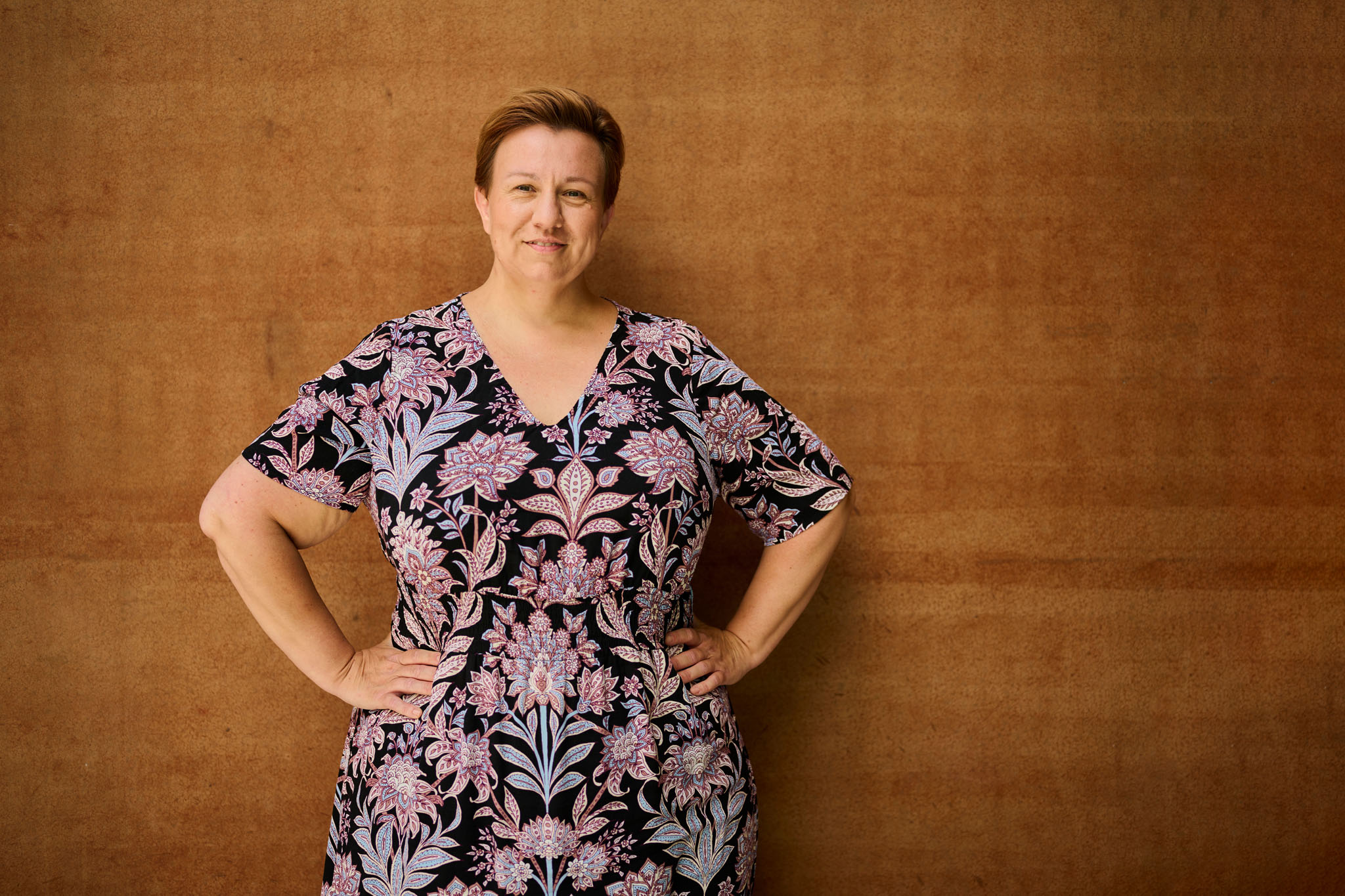 Kvinde får taget portrætbillede ved rustrød væg.