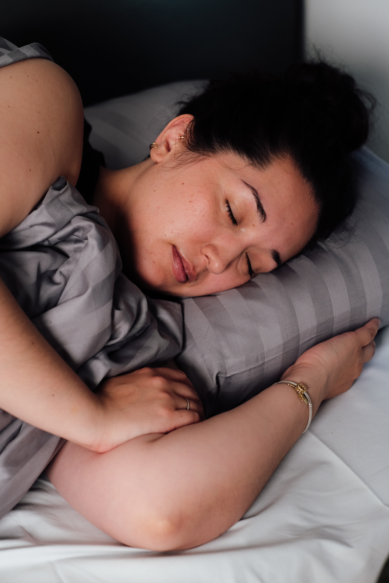 Kvinde sover i seng.