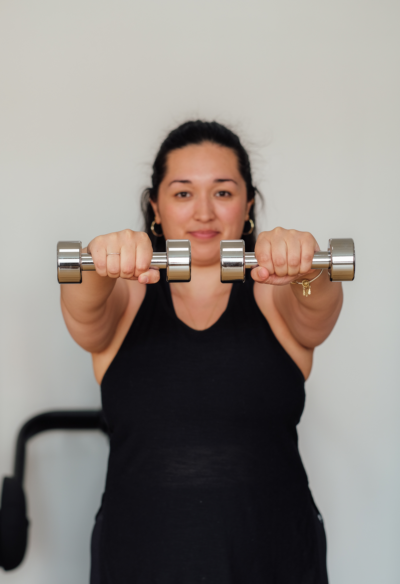 Kvinde løfter håndvægte og kigger direkte i kameraet.